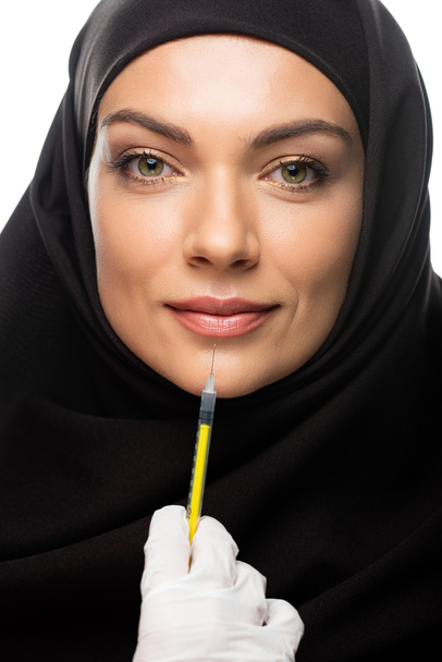 young Muslim woman in hijab having beauty injection isolated on white, lip augmentation concept - Foto, afbeelding