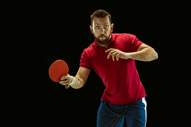 Young man playing table tennis on black studio background - Foto, Imagen