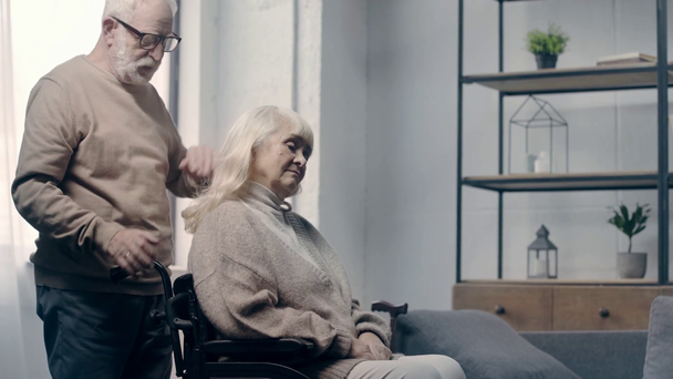 Senior man calming down woman with dementia in wheelchair  - Footage, Video
