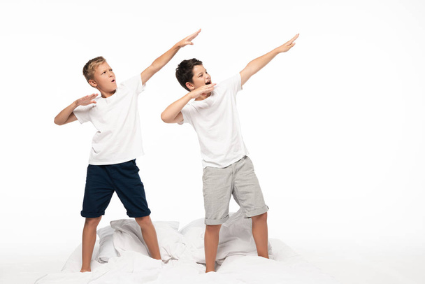 two brothers imitating archery while standing on bed  isolated on white - Valokuva, kuva