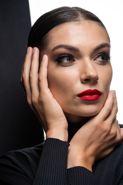 beautiful woman with red lips posing with hands near face isolated on white and black - Zdjęcie, obraz