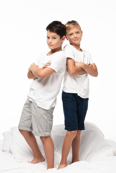 two cunning boys standing back to back with crossed arms and smiling at camera isolated on white - Fotografie, Obrázek