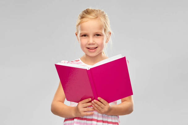 smiling little girl reading book - Fotoğraf, Görsel