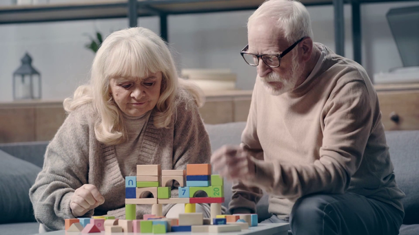 Seniorenpaar mit Demenz spielt mit Bauklötzen auf Sofa - Filmmaterial, Video