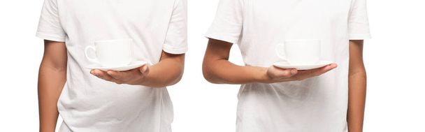 cropped view of two boys holding saucers with cups of coffee isolated on white, panoramic shot - Photo, Image