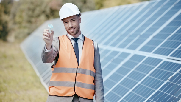 uśmiechnięty biznesmen pokazujący model baterii słonecznej  - Materiał filmowy, wideo