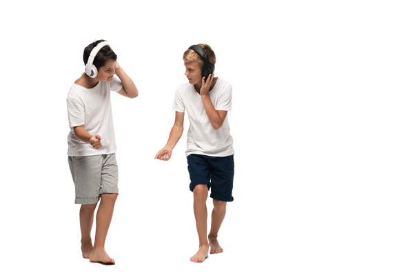 two brothers listening music in headphones and dancing on white background - Foto, Imagen