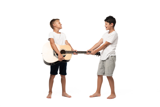two brothers looking at camera and dancing while listening music in headphones on white background - Φωτογραφία, εικόνα