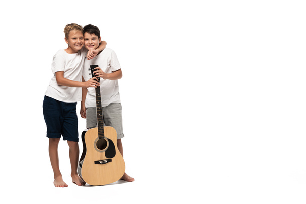 two brothers looking at camera and dancing while listening music in headphones on white background - Foto, Imagen
