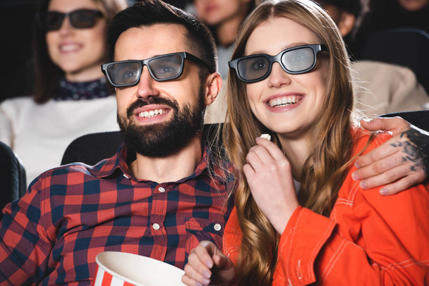 handsome boyfriend hugging smiling girlfriend in 3d glasses and watching movie in cinema  - Fotó, kép