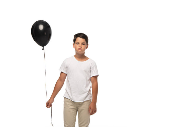trastornado chico sosteniendo negro globo mientras de pie aislado en blanco
 - Foto, Imagen