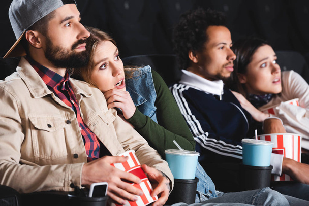 selective focus of scared multicultural friends watching movie in cinema  - Фото, изображение