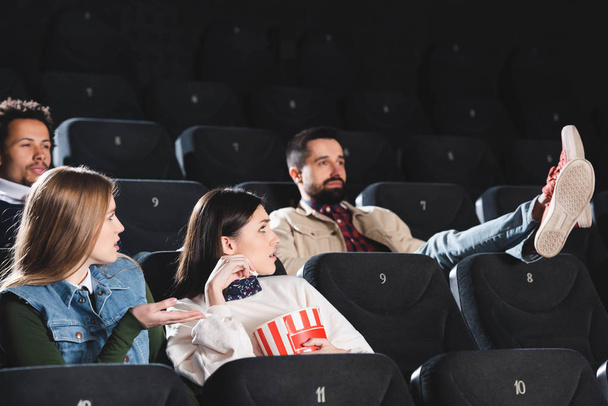 multicultural friends with popcorn looking at ill-mannered man in cinema  - Photo, Image