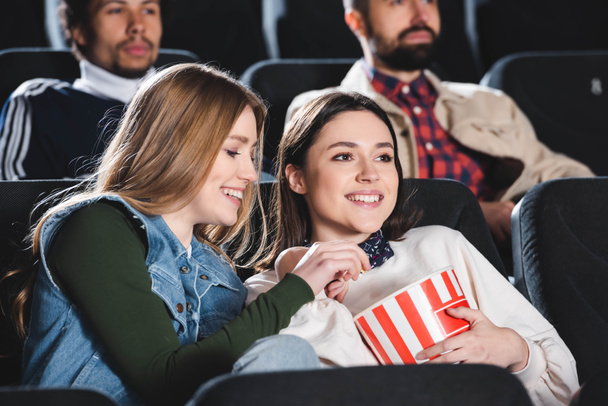 selektywne skupienie się na uśmiechniętych znajomych z popcornem oglądających film w kinie  - Zdjęcie, obraz