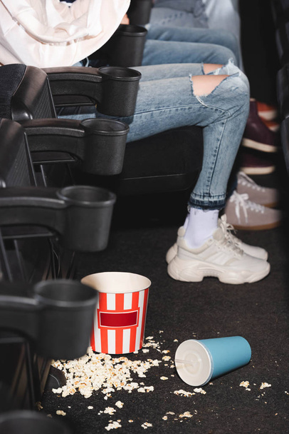 selective focus of popcorn and paper cup with soda on floor in cinema  - Foto, Bild