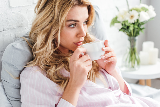attractive woman holding cup with coffee in bed  - Photo, Image