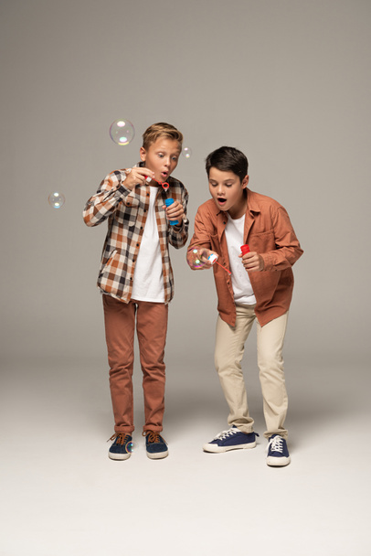 two brothers blowing soap bubbles isolated on grey - Fotografie, Obrázek