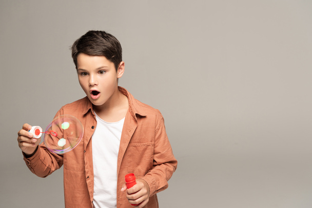 amazed boy looking at soap bubble isolated on grey - Fotoğraf, Görsel