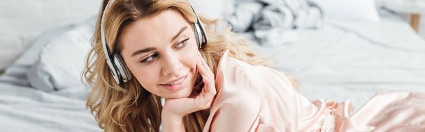 plano panorámico de chica alegre en auriculares escuchando música en el dormitorio
  - Foto, imagen