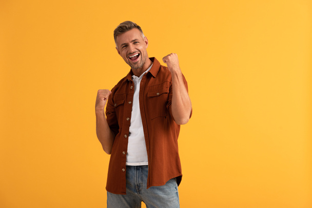 excited man with clenched fists isolated on orange  - Foto, Bild