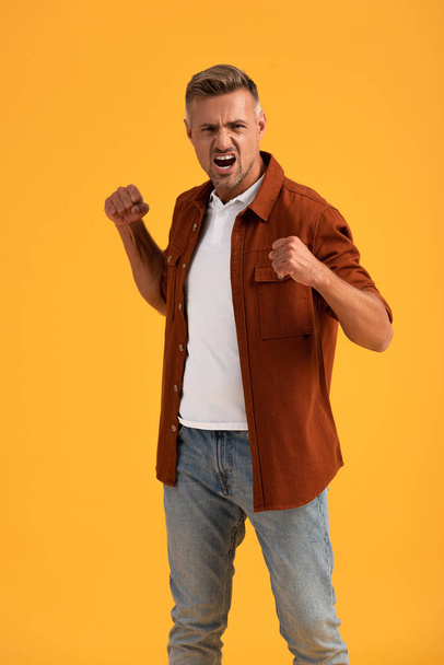 aggressive man with clenched fist screaming isolated on orange  - Fotografie, Obrázek