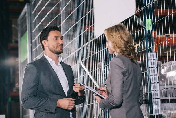 confident business partners talking while standing in warehouse - Photo, Image