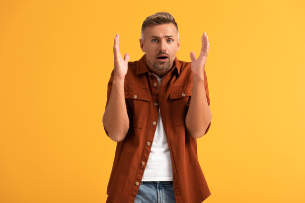 shocked man gesturing while looking at camera isolated on orange  - Foto, imagen