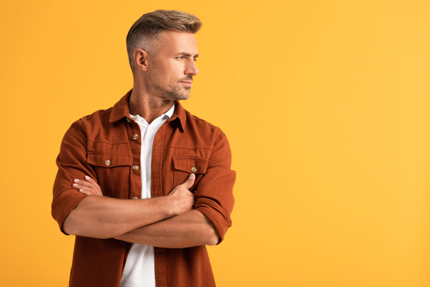 handsome man standing with crossed arms isolated on orange  - Fotografie, Obrázek