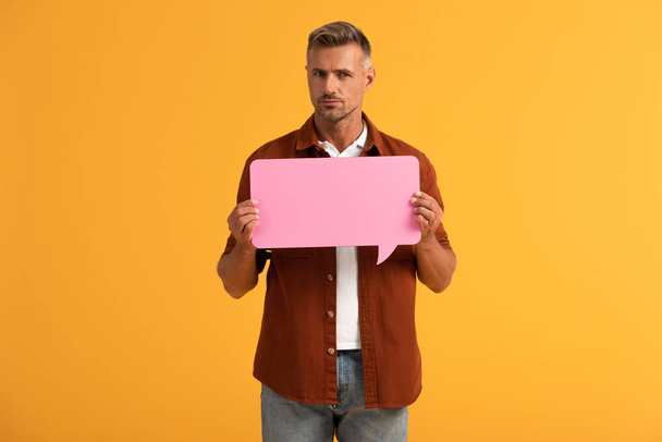 handsome man holding pink speech bubble isolated on orange  - Foto, immagini