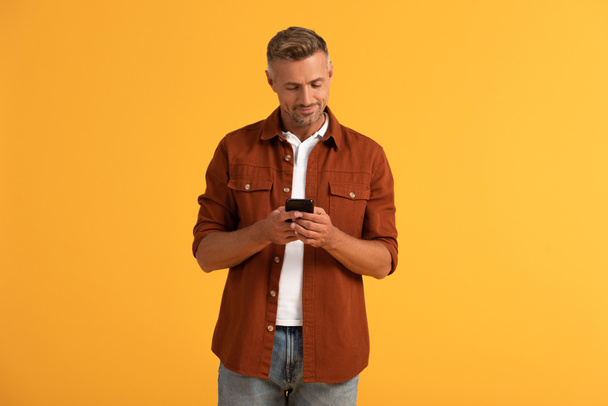 happy man using smartphone isolated on orange  - Фото, зображення