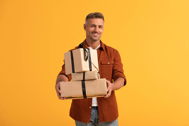 happy man holding presents isolated on orange  - Zdjęcie, obraz