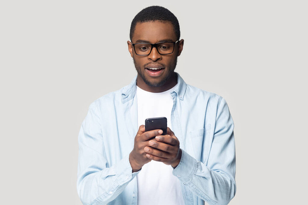 Head shot surprised African American man looking at phone screen - 写真・画像