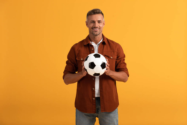cheerful man holding football isolated on orange  - Fotó, kép
