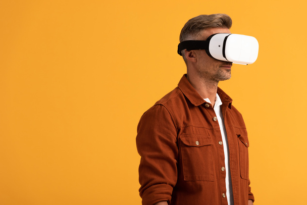 άνθρωπος σε εικονική πραγματικότητα ακουστικά που απομονώνονται σε πορτοκαλί  - Φωτογραφία, εικόνα