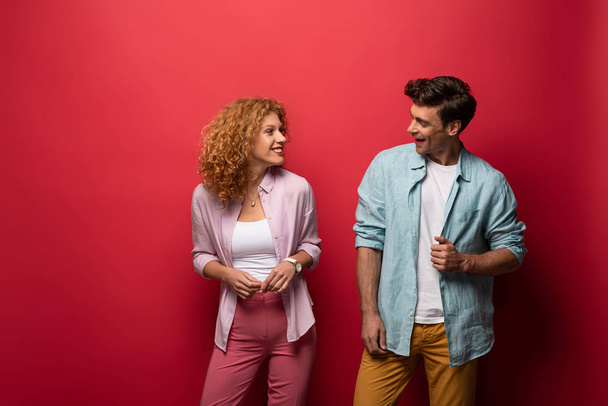 beautiful smiling couple in casual clothes, isolated on red - Foto, Imagen