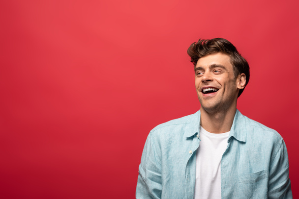 portrait of handsome laughing man in casual clothes isolated on red - Fotografie, Obrázek