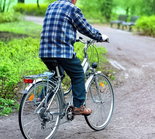Senior man riding bike in park - Photo, Image