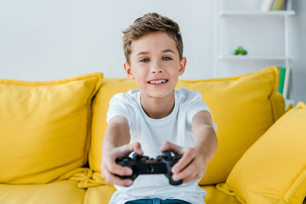 KYIV, UKRAINE - OCTOBER 2, 2019: selective focus of happy kid playing video game at home  - Foto, immagini