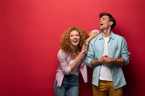 beautiful laughing couple in casual clothes isolated on red - Fotoğraf, Görsel