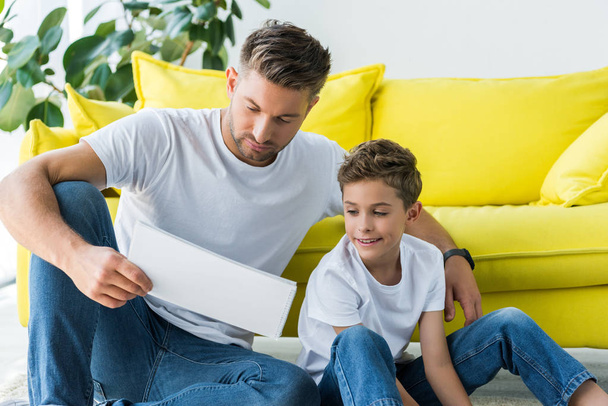 handsome father and cute son looking at notebook at home  - Fotoğraf, Görsel