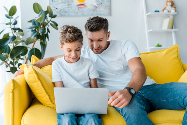 happy father and son looking at laptop at home  - Фото, зображення