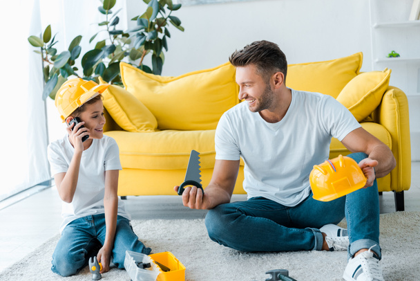 Ευτυχισμένος πατέρας κοιτάζει το γιο παίζει με walkie talkie  - Φωτογραφία, εικόνα