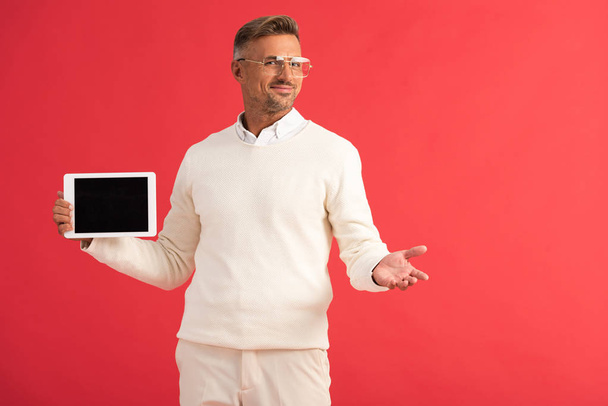 χαρούμενος άνθρωπος κρατώντας ψηφιακό δισκίο με λευκή οθόνη απομονώνονται σε κόκκινο  - Φωτογραφία, εικόνα