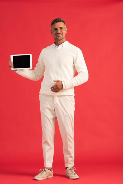 happy man holding digital tablet with blank screen on red  - Photo, Image