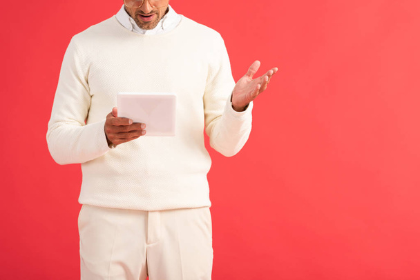 cropped view of surprised man gesturing while holding digital tablet isolated on red  - Foto, Imagem