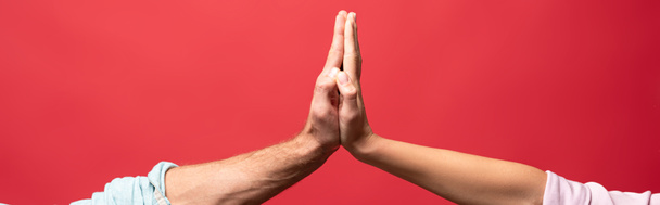 partial view of young couple giving high five, isolated on red - Fotoğraf, Görsel