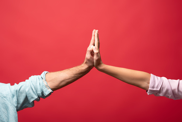 partial view of couple giving high five, isolated on red - Foto, imagen
