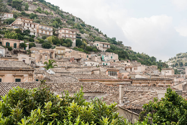 kleine huizen op een heuvel in de buurt van groene planten in modica, Italië  - Foto, afbeelding
