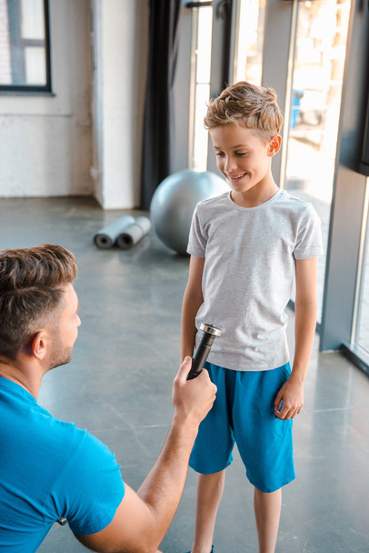 selective focus of father giving dumbbell to happy son  - Photo, Image