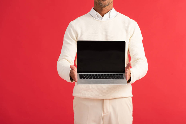 cropped view of man holding laptop with blank screen isolated on red  - Fotoğraf, Görsel